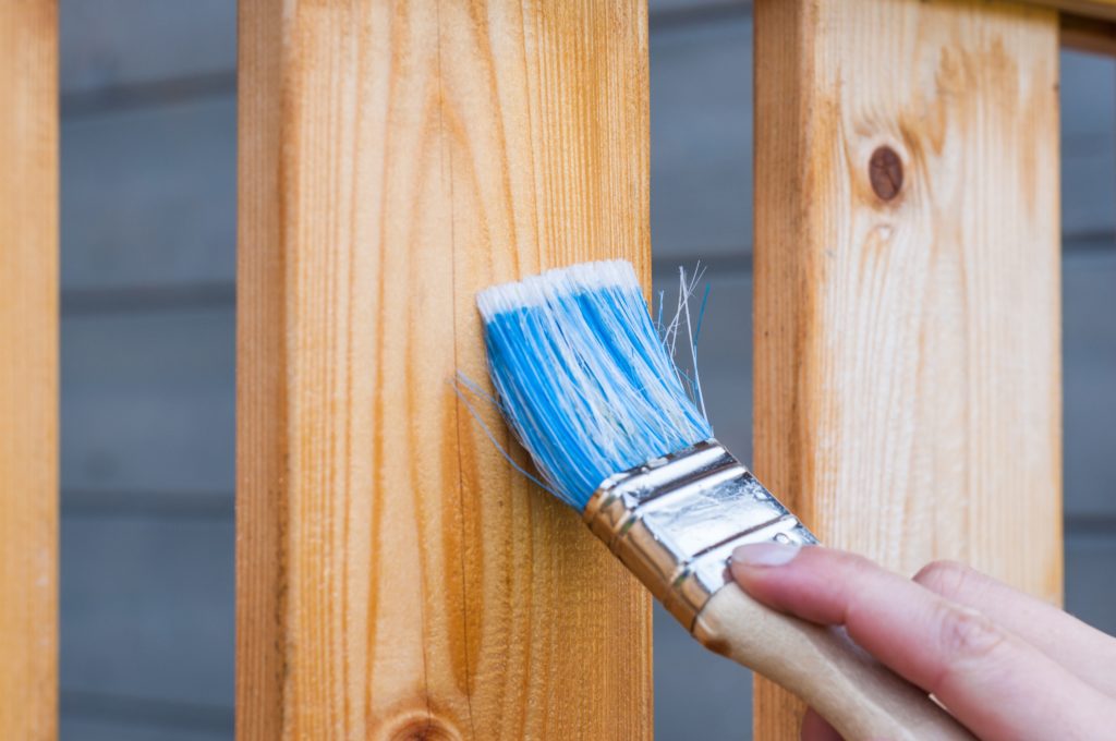 A paint brush applying varnish to some wood